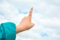 Child hand with exposed index finger raised up over blue sky and clouds. Gesture Royalty Free Stock Photo