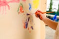 Child hand holding brush and painting with watercolour on brown paper. Kid drawing. hands and paint brushes. children art Royalty Free Stock Photo