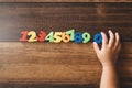 Child hand holding number zero with sets of other colorful numbers plastic toy on a wooden table Royalty Free Stock Photo