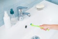 Child hand holding toothbrush under running water in bright bath Royalty Free Stock Photo