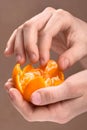 Child hand peeling ripe sweet tangerine