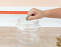 Child hand putting coin into plastic money bottle or piggy bank. Concept of saving money for the future or money growth Royalty Free Stock Photo