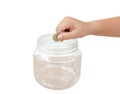 Child hand putting coin into transparent plastic money bottle or piggy bank isolated on white background with clipping path. Royalty Free Stock Photo