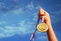Child hand raised, holding gold medal against sky. education, success, achievement, award and victory concept. Royalty Free Stock Photo