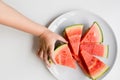 Child hand reaching for sliced watermelon on white plate Royalty Free Stock Photo