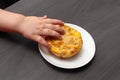Child hand takes fish muffin from plate. Royalty Free Stock Photo
