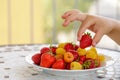 child hand taking bio yellow raspberries and red strawberries. close up Royalty Free Stock Photo