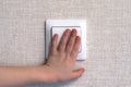 Child hand turning on the light with a wall switch Royalty Free Stock Photo