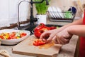 Child hands chopping a red bellpepper for a fresh vegetables sal