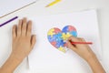 Child hands coloring puzzle heart with colored pencils. Top view. World autism awareness day concept