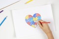 Child hands coloring puzzle heart with colored pencils. Top view. World autism awareness day concept Royalty Free Stock Photo