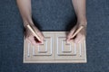 Child hands drawing lines in two-sided wooden stencil labyrinth
