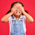 Child, hands and eyes cover on isolated red background with angry, mad or stubborn facial expression. Girl, kid and