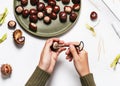 Child hands hold a hand drill tool and make a hole in the chestnut. Royalty Free Stock Photo