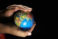 Child hands holding the Earth globe on black background. Royalty Free Stock Photo