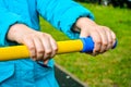 Child hands holding handle of children sports equipment on playground