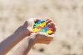 Child hands holding multicolored puzzle heart in the beach over sand. World autism awareness day background Royalty Free Stock Photo