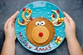 Child hands holding a plate with reindeer pancakes