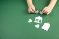 Child hands holding white paper house and heart on green background. Family home and real estate concept. Royalty Free Stock Photo