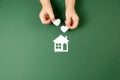 Child hands holding white paper house and heart on green background. Family home and real estate concept. Royalty Free Stock Photo