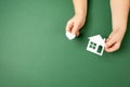 Child hands holding white paper house and heart on green background. Family home and real estate concept. Royalty Free Stock Photo