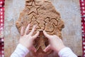 Child hands making from dough gingerbread man for