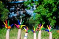 Child hands painted in bright colors isolated on summer nature background