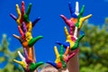 Child hands painted in bright colors isolated on summer nature background