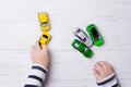 Child hands playing with miniature toy cars, wooden background, top view Royalty Free Stock Photo