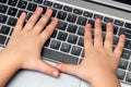 Child hands press buttons on laptop keyboard, child learning and playing on computer