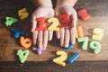 Child hands showing a colorful 123 numbers agains wooden table