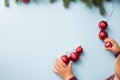 Child hands touching Christmas decoration red balls on blue background with green christmas tree, copy space. happy new year Royalty Free Stock Photo