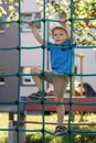 Child hanging on green rope net in city park Royalty Free Stock Photo