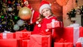 Child happy excited girl find gifts near christmas tree. Merry christmas. Kid wear santa hat hold wrapped christmas gift