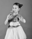 Child with happy face poses with candy on green background. Lady holds long lollipop. Girl eats big colorful sweet Royalty Free Stock Photo