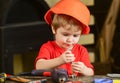 Child in hard hat, helmet playing with hex bolts as builder or repairer, handcrafting. Toddler on busy face plays with