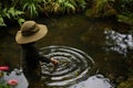 child in hat making rain ripples in pond Royalty Free Stock Photo