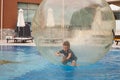 Little boy have fun inside big plastic balloon on the water of swimming pool on the summer resort. Kid inside big inflatable Royalty Free Stock Photo