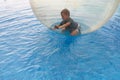 Little boy have fun inside big plastic balloon on the water of swimming pool on the summer resort. Kid inside big inflatable Royalty Free Stock Photo