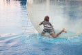 Little boy have fun inside big plastic balloon on the water of swimming pool on the summer resort. Kid inside big inflatable Royalty Free Stock Photo