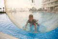 Little boy have fun inside big plastic balloon on the water of swimming pool on the summer resort. Kid inside big inflatable Royalty Free Stock Photo