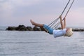 Child have fun riding on rope swing over the water. Happy childhood. Vacation at sea with children