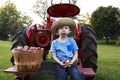 Child having fun apple picking and sitting on a red antique tractor Royalty Free Stock Photo