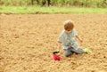 Child having fun with little shovel and plant in pot. Planting in field. Planting seedlings. Little helper in garden