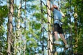 Child having fun at outdoor extreme adventure rope park. Active childhood, playing outdoors. Royalty Free Stock Photo