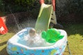 Child having fun playing in water in a garden paddling pool the boy is happy and smiling Royalty Free Stock Photo