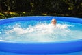 A child is having fun in a rubber pool. A girl splashes in an inflatable pool in the garden on a sunny summer day Royalty Free Stock Photo