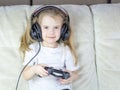 A child with headphones playing. Happy little girl playing video game Royalty Free Stock Photo