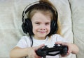 A child with headphones playing. Happy little girl playing video game Royalty Free Stock Photo