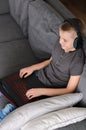 Child in headphones playing online video game on laptop computer at home. Happy boy sitting and use pc Royalty Free Stock Photo